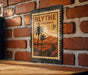 A vintage-style metal sign with a palm tree and mountains, mounted on a brick wall.