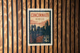 A vintage-style postage stamp from the United States, featuring the city of Cincinnati, Ohio, with a bridge and skyline in the background.