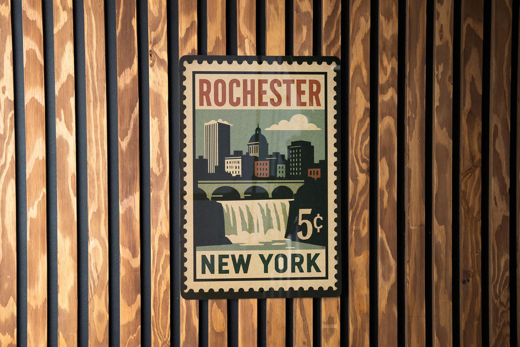 A vintage postage stamp from Rochester, New York, featuring a cityscape and a waterfall, mounted on a wooden wall.