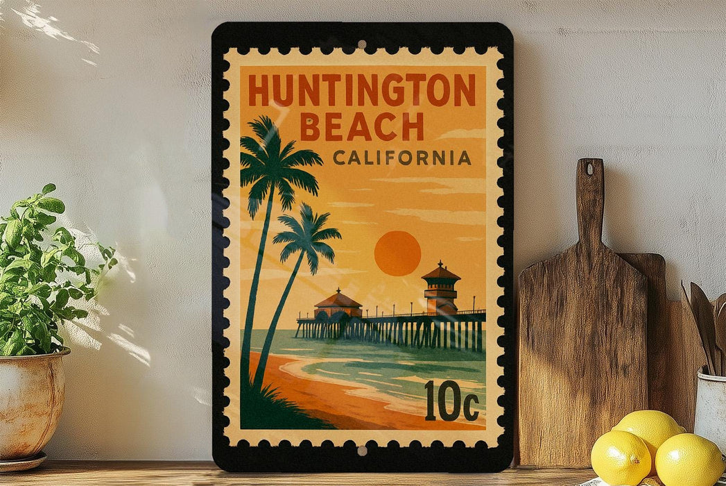 A framed poster of Huntington Beach, California, featuring a tropical beach scene with palm trees, a pier, and a sunset.