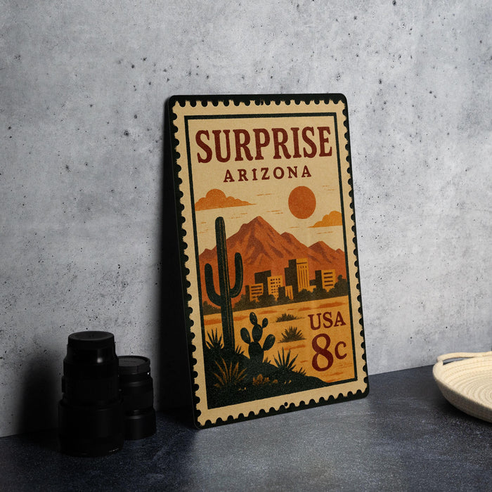 A vintage-style metal stamp depicting a desert landscape with mountains, cacti, and a city skyline, along with the text "Surprise Arizona USA 8c".