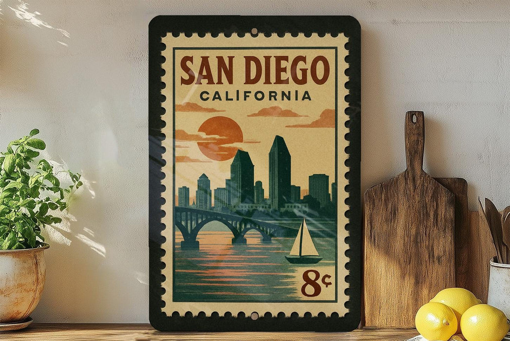 A framed vintage-style poster of San Diego, California, featuring a cityscape with a bridge and sailboat, is displayed on a wall next to kitchen utensils and a potted plant.