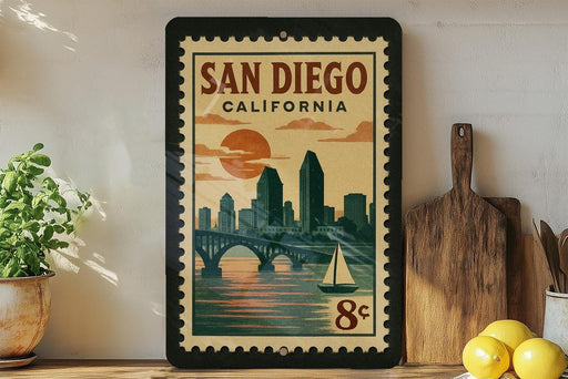 A framed vintage-style poster of San Diego, California, featuring a cityscape with a bridge and sailboat, is displayed on a wall next to kitchen utensils and a potted plant.