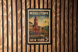 A vintage-style postage stamp from New York, featuring a cityscape with a clock tower, mounted on a wooden wall.