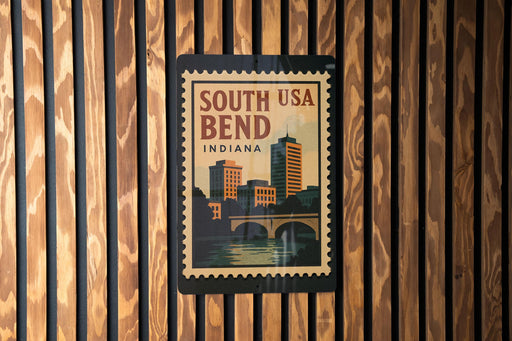 A vintage-style poster of South Bend, Indiana, featuring a cityscape and a bridge, is displayed on a wooden wall.