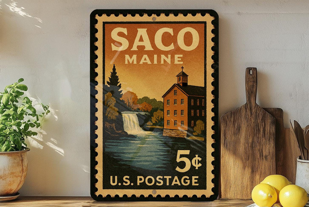 A vintage postage stamp from Maine, featuring a scenic illustration of a waterfall and a building, displayed on a shelf next to a wooden cutting board and some lemons.