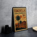 A vintage-style stamp depicting a palm tree and sunset, with the text "COACHELLA CALIFORNIA 50¢" printed on it.