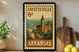 A framed vintage-style poster of Fayeville, Arkansas, featuring a castle-like building surrounded by trees and mountains.