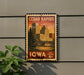 A vintage-style postage stamp from Cedar Rapids, Iowa, featuring a cityscape with a bridge and trees, mounted on a wall.