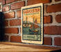 A vintage postage stamp from Gloucester, Massachusetts, featuring a sailboat on the water, mounted on a brick wall.