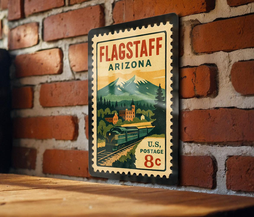 A vintage-style metal stamp depicting a scenic landscape with mountains, a train, and a small town, mounted on a brick wall.
