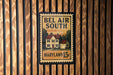 A framed poster with the text "BEL AIR SOUTH" and "MARYLAND 15¢" is displayed on a wooden wall.