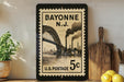 Bayonne, New Jersey postage stamp with a bridge and steam pipes, 5 cents, and a wooden cutting board and lemons on a shelf.