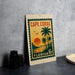 A vintage-style metal sign with a tropical beach scene and palm trees, featuring the text "CAPE CORAL FLORIDA 6c".