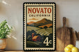 a vintage-style metal sign with a landscape scene and a barn, placed on a wooden surface next to a wooden cutting board and some lemons.