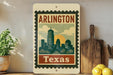 A vintage-style metal sign displaying the text "ARLINGTON TEXAS" with a stylized illustration of a city skyline.
