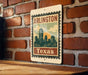 A metal sign with the text "ARLINGTON TEXAS" and an illustration of a city skyline, mounted on a brick wall.