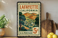 A vintage postage stamp from Louisiana, California, with a scenic illustration of a rural landscape and a church, displayed on a shelf next to a wooden cutting board and some lemons.