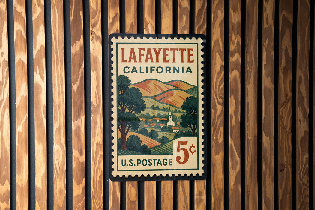 A vintage postage stamp from Louisiana, California, featuring a landscape with hills and a church, mounted on a wooden wall.