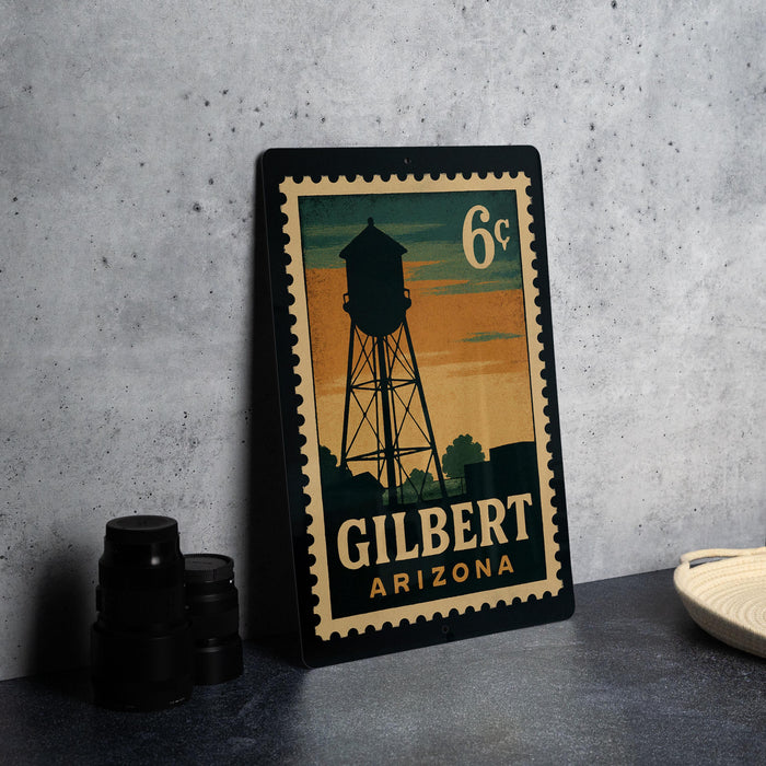A vintage postage stamp featuring a water tower in Gilbert, Arizona, with the text "6c" and "GILBERT ARIZONA" printed on it.
