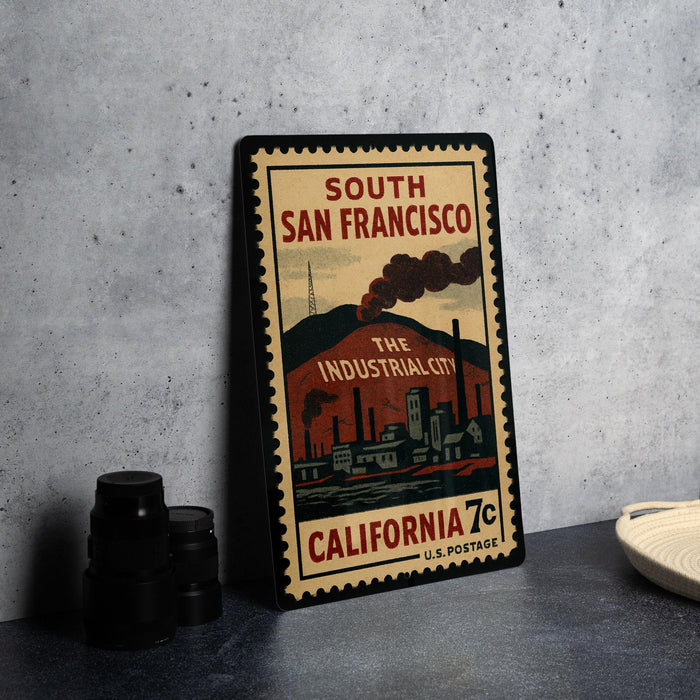 A vintage-style postage stamp from the United States, featuring an illustration of a cityscape with industrial buildings and smoke stacks.