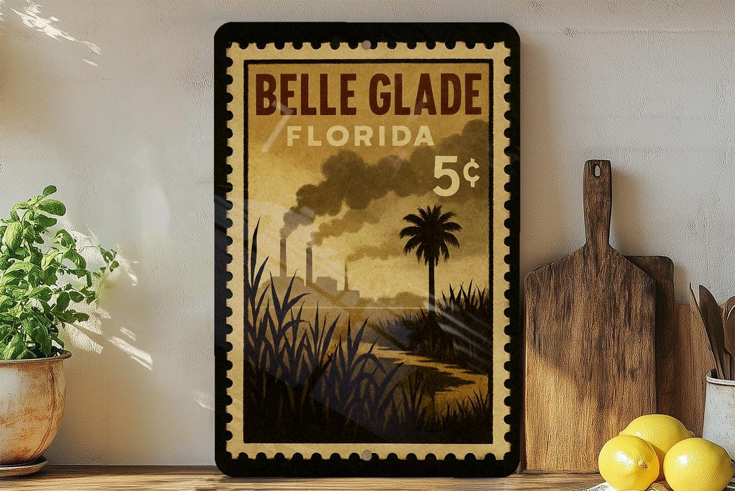 A framed poster of Belle Glade, Florida, with a tropical landscape and industrial smokestacks, is displayed on a shelf next to a wooden cutting board and a potted plant.