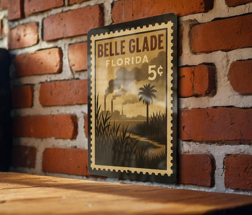 A vintage-style postage stamp from Belle Glade, Florida, featuring a palm tree and a river, is displayed on a brick wall.