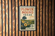 A vintage-style metal sign with a floral design and text, mounted on a wooden wall.