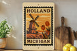 A framed poster of a windmill and tulips, with the text "HOLAND MICHIGAN" on it, is displayed on a shelf next to a wooden cutting board and some kitchen utensils.