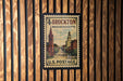 A vintage postage stamp from the United States of America, featuring a cityscape and a church, is displayed on a wooden wall.