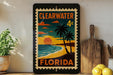 A framed poster of a beach scene with palm trees and a sunset, depicting Clearwater, Florida.
