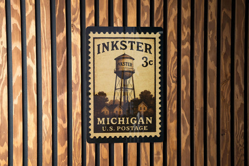 A vintage-style postage stamp featuring a water tower, mounted on a wooden wall.