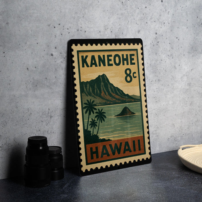 A vintage-style postage stamp from Hawaii, featuring a mountain landscape and palm trees, is displayed on a countertop next to some black camera lenses.