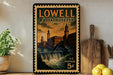 A vintage postage stamp from Lowell, Massachusetts, featuring a cityscape with a waterfall, displayed on a shelf next to a wooden cutting board and some lemons.