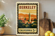A vintage-style postage stamp depicting the city of Berkeley, California, with a tall bell tower and a colorful sunset in the background.