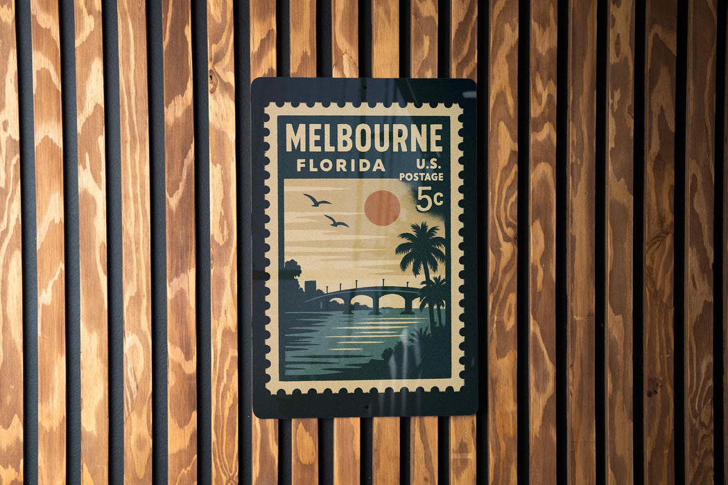 A vintage postage stamp from Melbourne, Florida, featuring a sunset and palm trees, is displayed on a wooden wall.