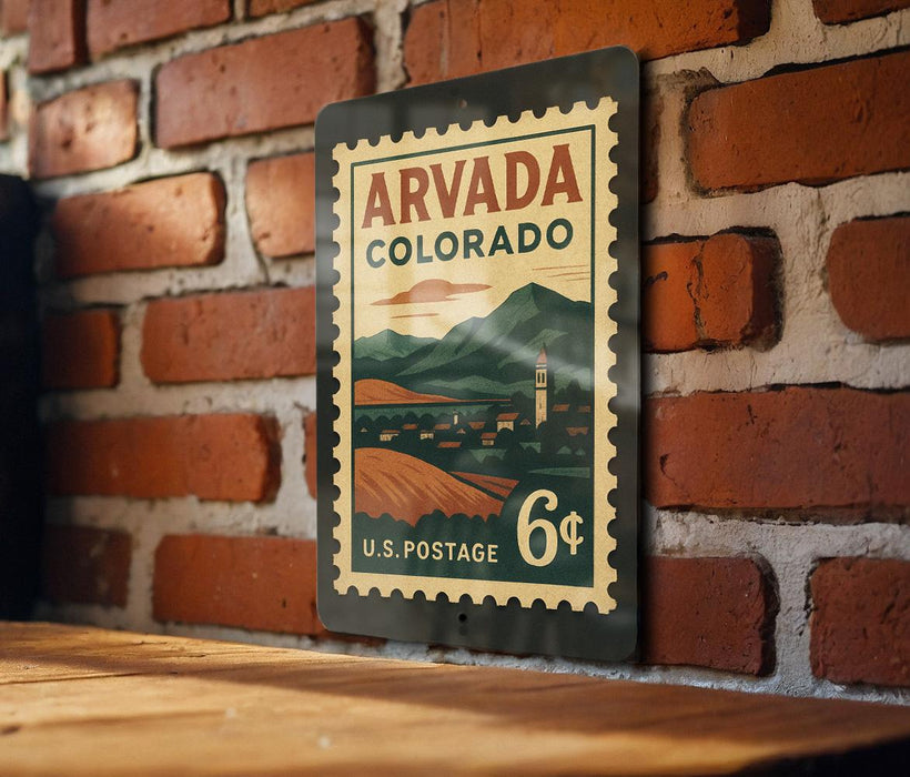 A vintage-style postage stamp from the United States of America, featuring a mountain landscape and a small town, mounted on a brick wall.