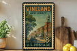 A vintage postage stamp from New Jersey, featuring a street scene with a clock tower, is displayed on a shelf next to a wooden cutting board and some lemons.