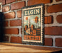 A vintage-style metal sign with a cityscape and a water tower, mounted on a brick wall.