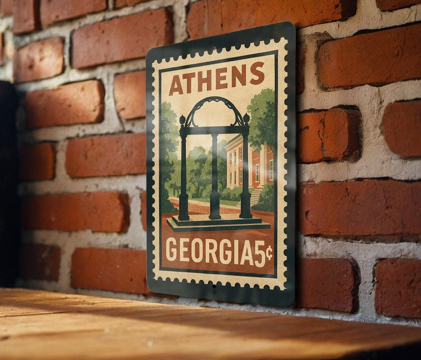 A metal sign with a vintage-style illustration of the University of Georgia's Archway, mounted on a brick wall.