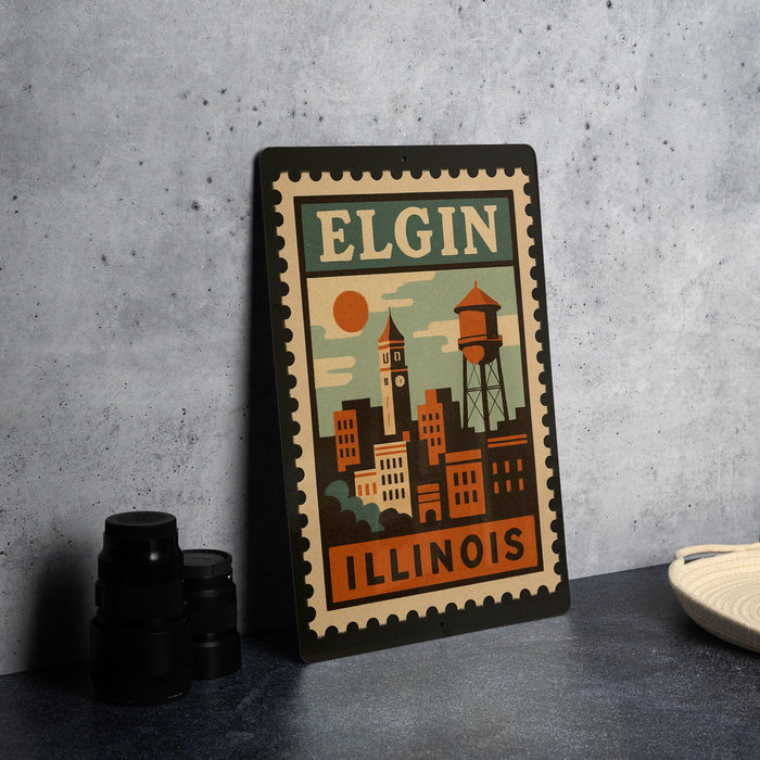 A vintage-style metal sign with the text "ELGIN ILLINOIS" and an illustration of a cityscape, placed on a gray countertop next to some black camera lenses.