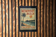 A vintage-style poster of Newport Beach, California, featuring a palm tree and a pier, is displayed on a wooden wall.