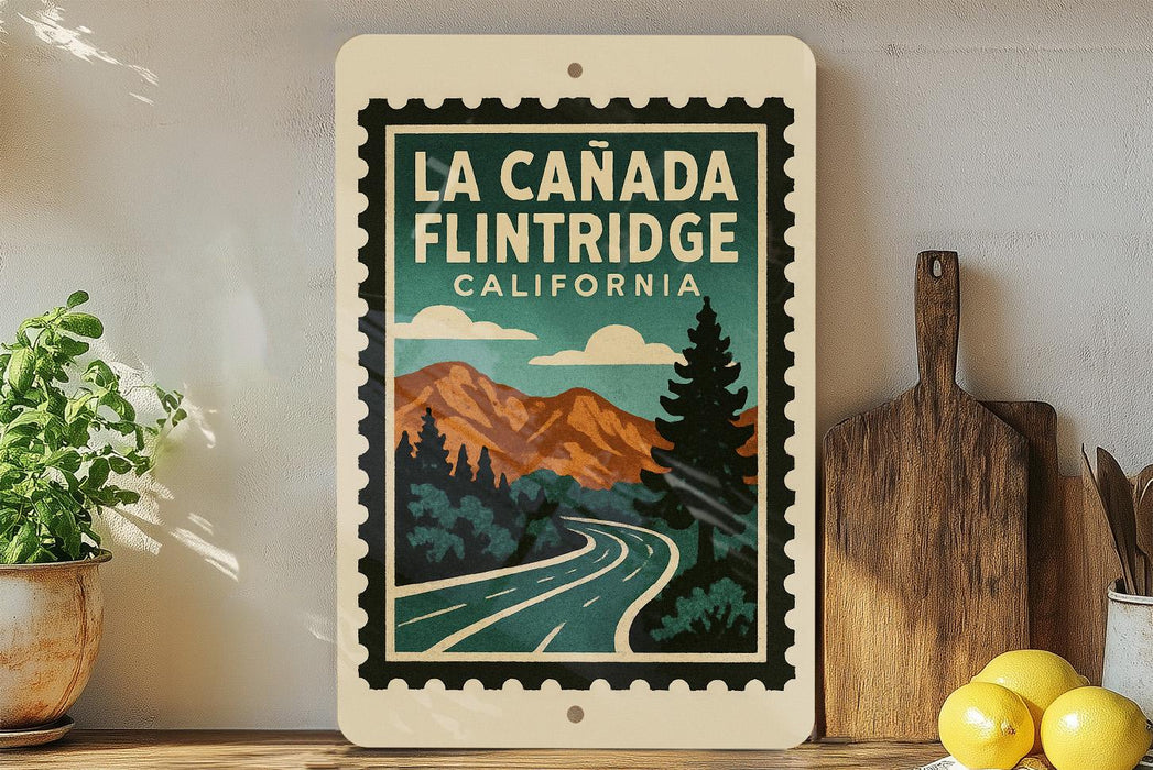 A framed poster of La Canada Flintridge, California, featuring a scenic mountain landscape with a winding road and pine trees.