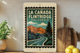 A framed poster of La Canada Flintridge, California, featuring a scenic mountain landscape with a winding road and pine trees.