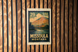 A vintage-style postage stamp from the United States, featuring a scenic landscape of Missoula, Montana.