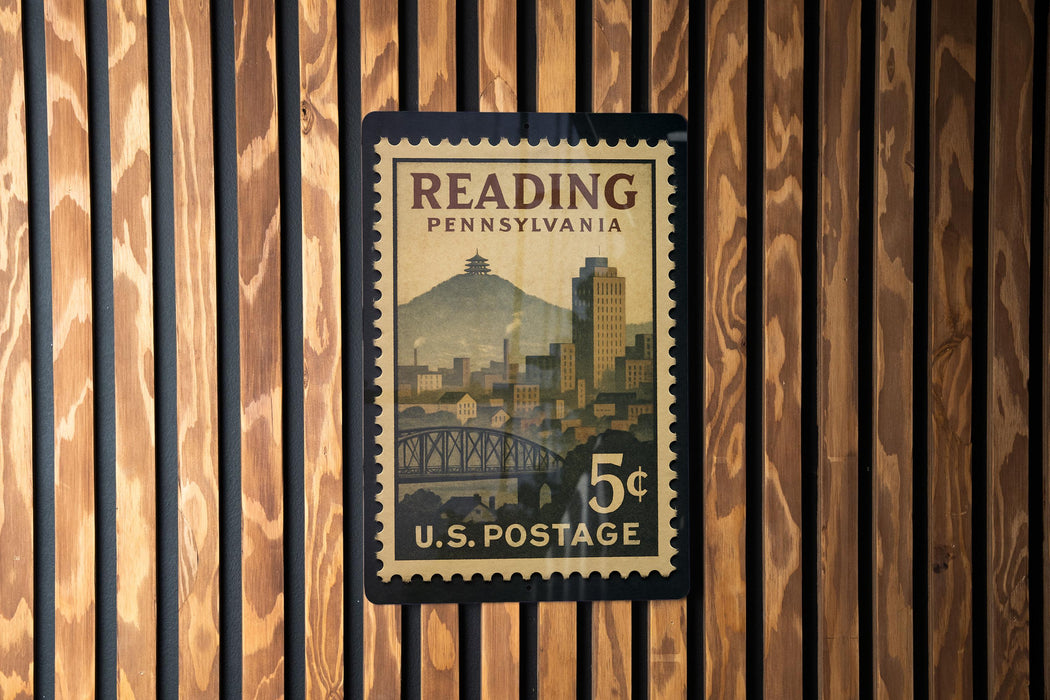 A U.S. postage stamp from Pennsylvania featuring a cityscape and a bridge, mounted on a wooden wall.