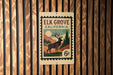 A metal sign with a stamp-like design, mounted on a wooden wall.