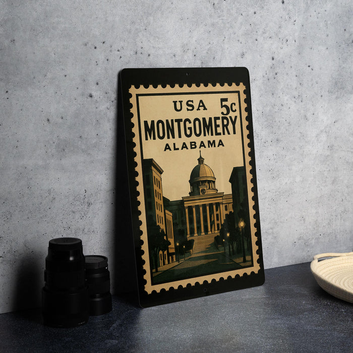 A framed vintage postage stamp from Alabama, featuring an illustration of the Montgomery building, is displayed on a table.