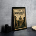 A framed vintage postage stamp from Alabama, featuring an illustration of the Montgomery building, is displayed on a table.