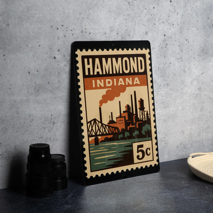 A vintage-style stamp depicting a cityscape with a bridge and industrial buildings, placed on a countertop next to some black camera lenses.
